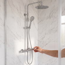 Hand adjusting the chrome exposed thermostatic bar valve with riser rail, rain head and handset