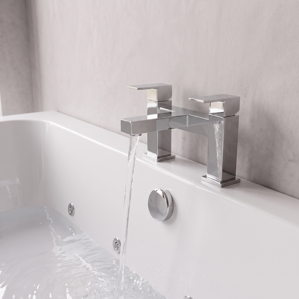 Chrome Slade two-pillar bath filler tap filling the whirlpool bath, with chrome overflow below