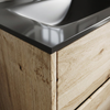 Detail of glossy black glass basin edge and rustic light oak veneer grain on the Akron vanity