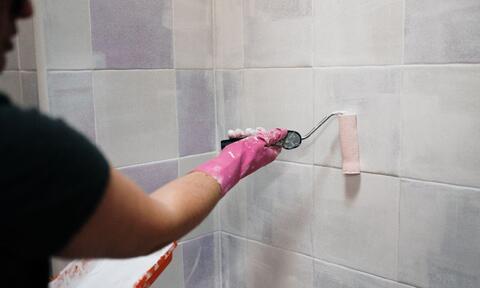 Man Painting Bathroom Wall And Wearing Pink Glove