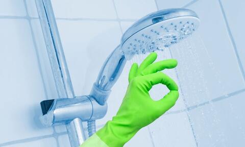 Hand In Green Gloves Next to Shower Head