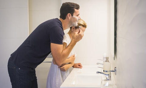 A Man Shaving In Front Of a Bathroom Mirror