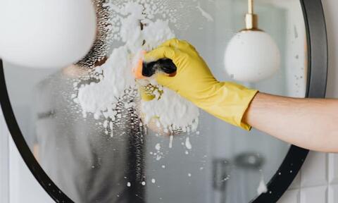 Man Hand Cleaning A Bathroom Mirror by Using Shaving Foam